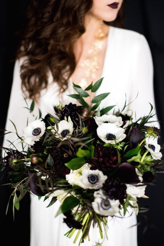 a contrasting wedding bouquet of white anemones, deep purple callas and asters, greenery and dark foliage