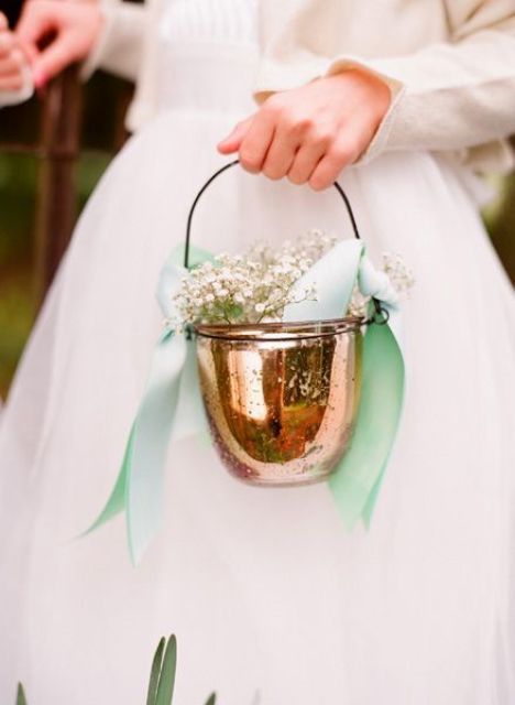 a copper jar used as a basket with green bows and baby's breath is a unique take on a traditional piece
