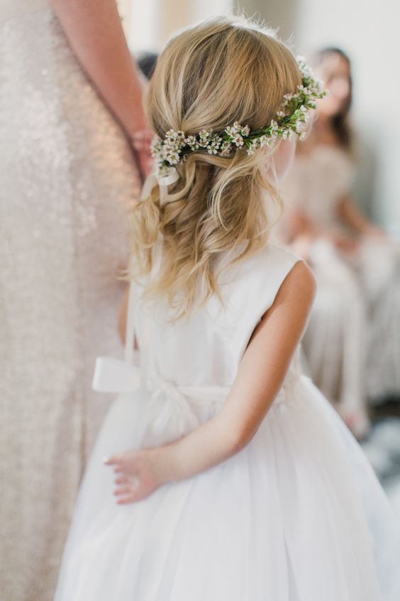 a delicate half updo with waves down and a bump, a white flower crown for an accent is a very chic and beautiful idea