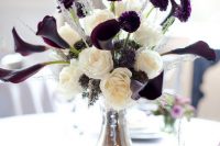a fantastic wedding centerpiece of a silver jug, white peony roses, deep purple calla lilies and ranunculus, grasses is wow