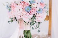 a gorgeous wedding bouquet of rose quartz roses and peonies and some blue blooms and long blush ribbons is amazing