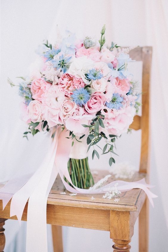 a gorgeous wedding bouquet of rose quartz roses and peonies and some blue blooms and long blush ribbons is amazing