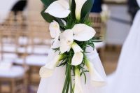 a lovely wedding decoration – a white curtain accented with white callas and orchids plus large leaves is a pretty idea
