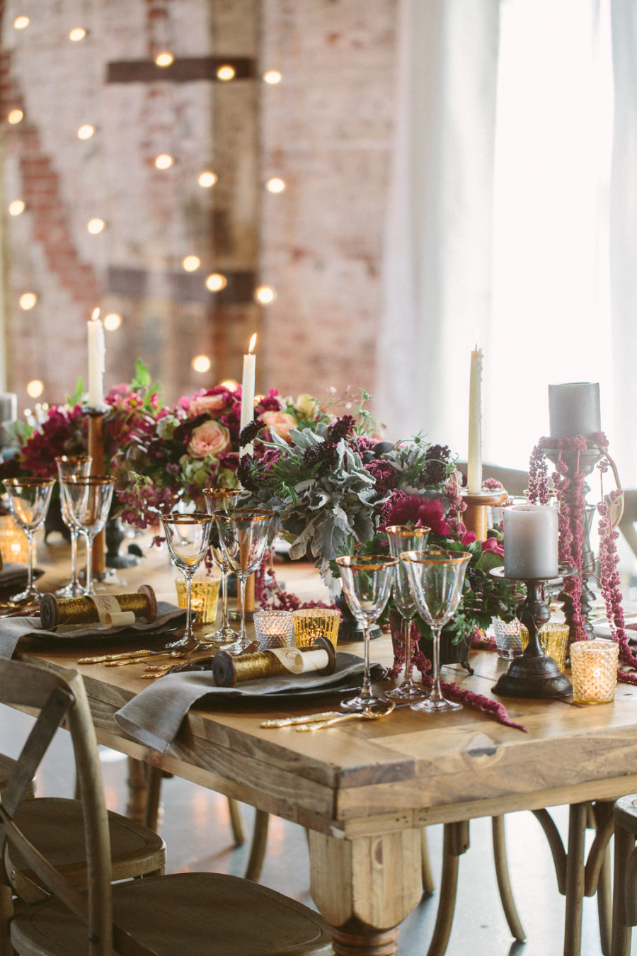 A lush and moody Sleeping Beauty wedding tablescape with moody florals, pale greenery, candles, gold rimmed glasses