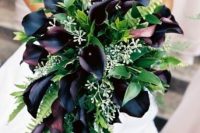 a lush wedding bouquet of deep purple callas, greenery, fern and white fillers is a very chic and bold idea