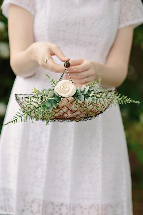a mini wire basket with greenery and a bloom is a chic idea with a rustic feel