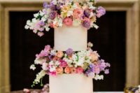 a modern white wedding cake with super bright and blush blooms between the tiers looks wow