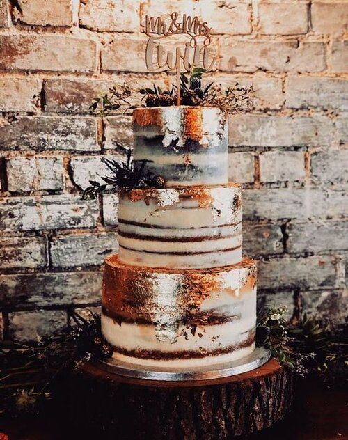 a naked wedding cake with gold leaf, berries, thstles, dried branches and a calligraphy topper