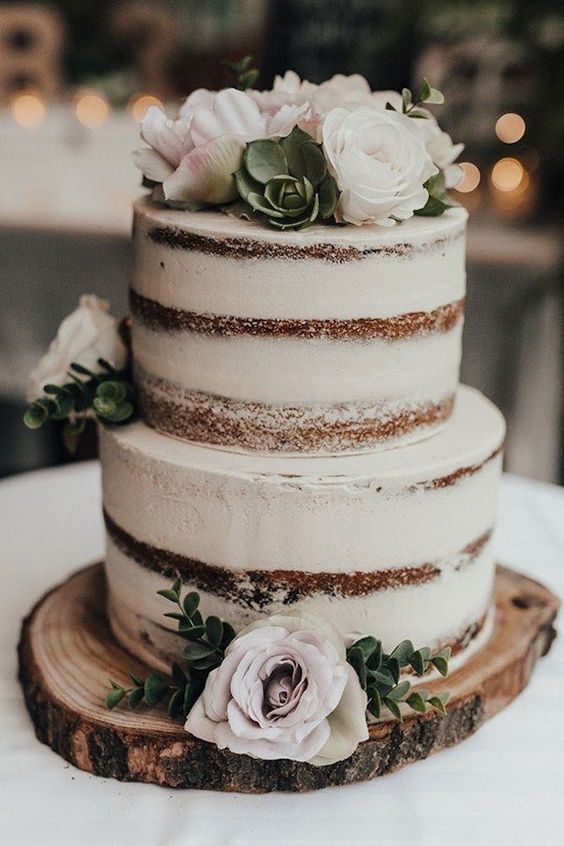 a neutral naked wedding cake with succulents, greenery and light pink blooms for a rustic wedding