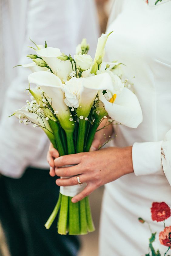 a pretty and chic wedding bouquet of white calla lilies and white baby's breath is a chic and cool idea for a wedding