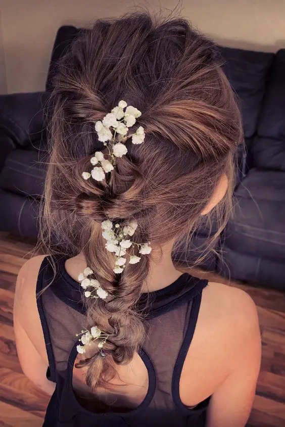 a pretty messy boho braid with a messy volume on top and some baby's breath tucked into the braid