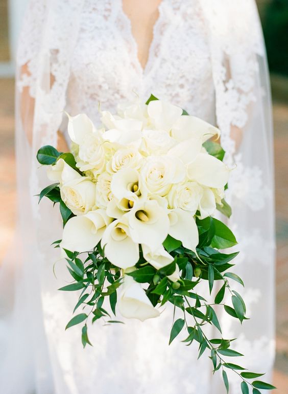 a pretty white wedding bouquet of roses and calla lilies plus greenery is a stylish idea for a spring or summer bride