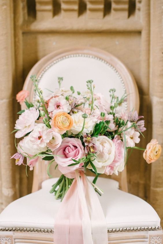 a refined dimensional rose quartz wedding bouquet with mellow yellow blooms and some greenery plus long pink ribbons is amazing