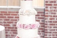 a romantic white wedding cake with blush and white blooms between the tiers