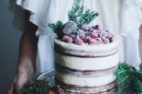 a semi naked wedding cake with sugared cranberries and pinecones on top is perfect for a winter or Christmas wedding