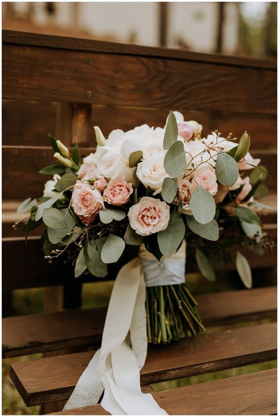 a simple and lovely wedding bouquet of white and blush roses and greenery plus long white ribbons is a very cool idea