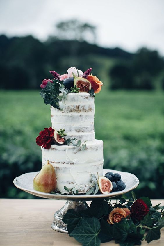 a simple semi naked wedding cake with fruits and foliage on top plus some bold blooms for a fall wedding