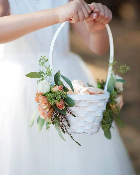 a simple white basket to carry flower petals adorned on each side with spray roses and seeded eucalyptus