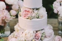 a subtle white textural wedding cake with white and blush blooms is very tender and cute