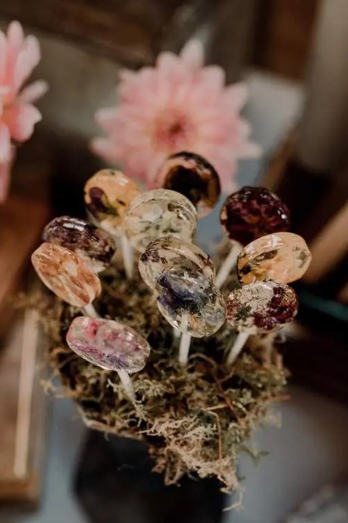 a vase with moss and clear lollipops with edible flowers is amazing for your wedding dessert table, they are very affordable