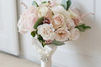 a very delicate and chic blush wedding bouquet of roses, astilbe and some greenery with a white ribbon wrap and a glam brooch is cool
