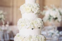 a white patterned wedding cake with white blooms between the tiers is very elegant and very chic