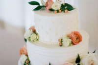 a white textural wedding cake with fresh blooms and a Mickey Mouse LOVE topper