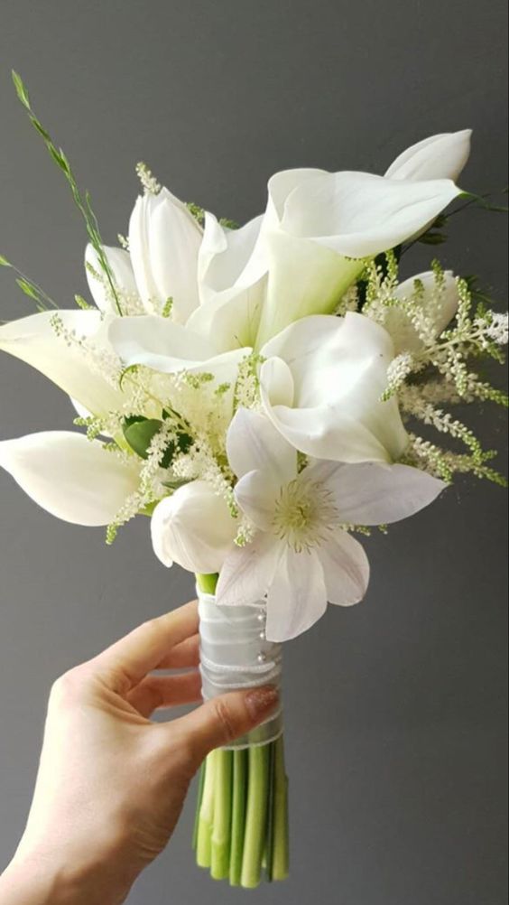 a white wedding bouquet of white calla lilies and white blooms, greenery and some bouquet fillers is chic