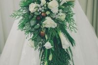 a winter wedding bouquet of lots of greenery and fern, white roses and calla lilies, berries and pinecones is super chic