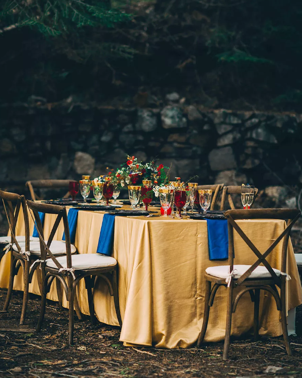 the Beauty and the Beast inspired tablescape done in gold, bold blue and deep red plus gold rim glasses and bright florals