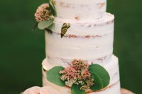 a naked wedding cake with pink blooms and leaves is a nice idea for a spring or summer wedding