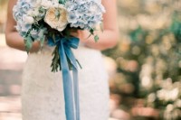 a romantic wedding bouquet of blue hydrangeas and some neutral peony roses accented with long blue ribbons is a very cool and stylish idea
