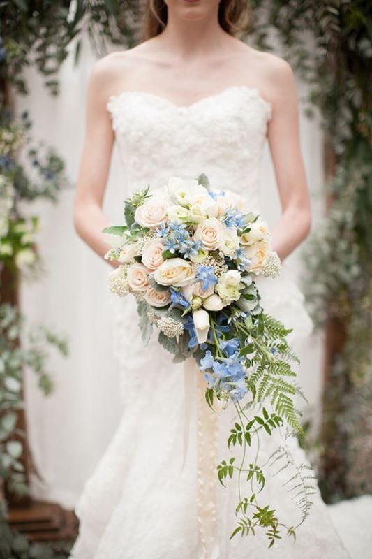 a chic cascading wedding bouquet of blush blooms, serenity blue and white ones plus some greenery going down is amazing