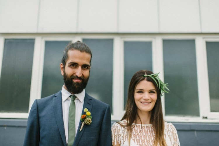 a grey suit, a white shirt,a  green tie, a full beard and a man bun for a stylish and chic boho groom look