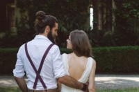 tan pants, a white shirt, burgundy suspenders, a full beard and a man bun for a simple and cool boho groom’s look
