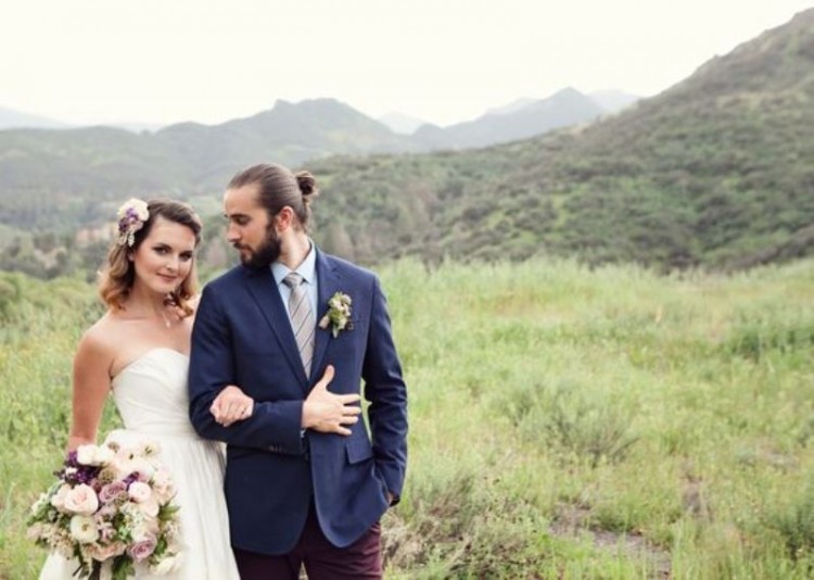 a navy blazer, purple velvet pants, a striped tie and a white shirt, a full beard and a man bun for a lovely boho groom's outfit
