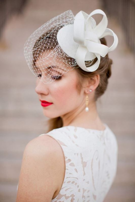 a mini birdcage veil with an oversized white bow on top is a pretty and modern idea for a refined bride