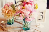 a cluster wedding centerpiece of jars, pink peonies, freesias, billy balls and pale leaves is a cool and chic idea for a wedding