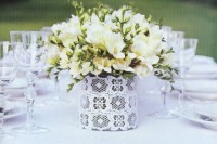 a chic neutral wedding centerpiece of a lace-inspired vase and white freesias perfectly accents the neutral wedding tablescape