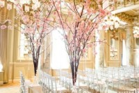 a refined formal wedding ceremony space with tall cherry blossom branches in crystal vases that embrace the season and give the space a strong spring feel