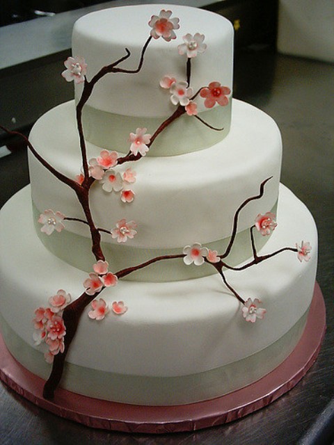 a neutral wedding cake with ribbon and sugar cherry blossom is a lovely idea for a spring or Japanese wedding