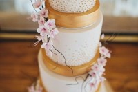 a refined white and gold wedding cake with polka dots and super delicate pink cherry blossom is a gorgeous idea for a formal spring wedding