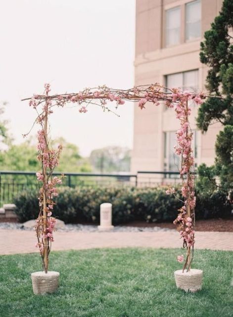 a delicate spring wedding arch decorated with pink cherry blossom is a lovely idea for the blooming season, it looks out of the box and romantic