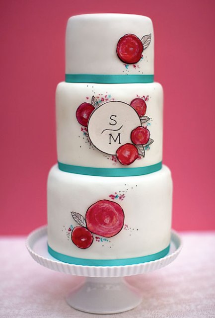 a white wedding cake with blue ribbons, painted blooms, monograms in a circle is a lovely and bright idea to go for