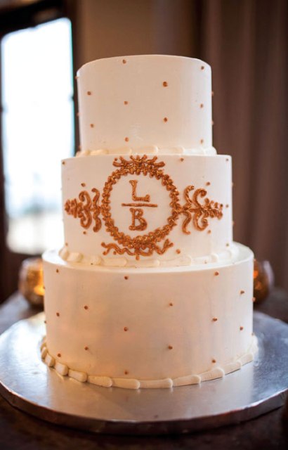 a white wedding cake with gold polka dots, gold patterns and monograms is a pretty and elegant idea to rock for a refined wedding