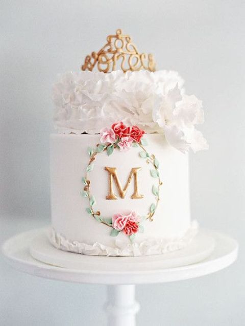 a white wedding cake with bold blooms and leaves, with a sugar bloom tier and a crown on top is a very cool stylish option