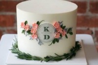 a white wedding cake with sugar blooms, greenery and a monogram in a circle is a stylish idea for a spring or summer wedding