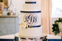 a navy and white wedding cake with plain and polka dot tiers plus navy ribbons and monograms is a cool idea for a nautical wedding