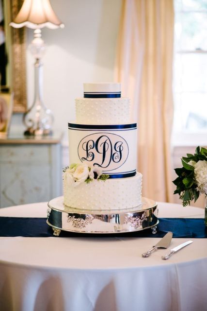 a navy and white wedding cake with plain and polka dot tiers plus navy ribbons and monograms is a cool idea for a nautical wedding