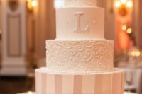 a white wedding cake with patterned and a striped tier, plus a monogram and a sugar bloom on top is a stylish and tasty idea